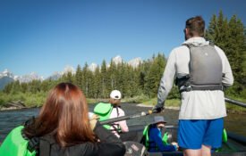river guide on the snake river with the teton mountains in the background